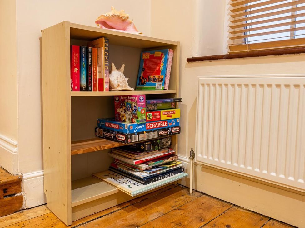 A bookshelf with books and board games in a living room