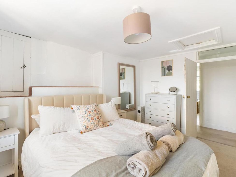 A bedroom with a bed, dresser, mirror, and lamp at the property