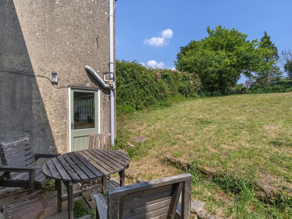 A garden with a wooden table and chairs outside a house at The Old Barn in Manchester