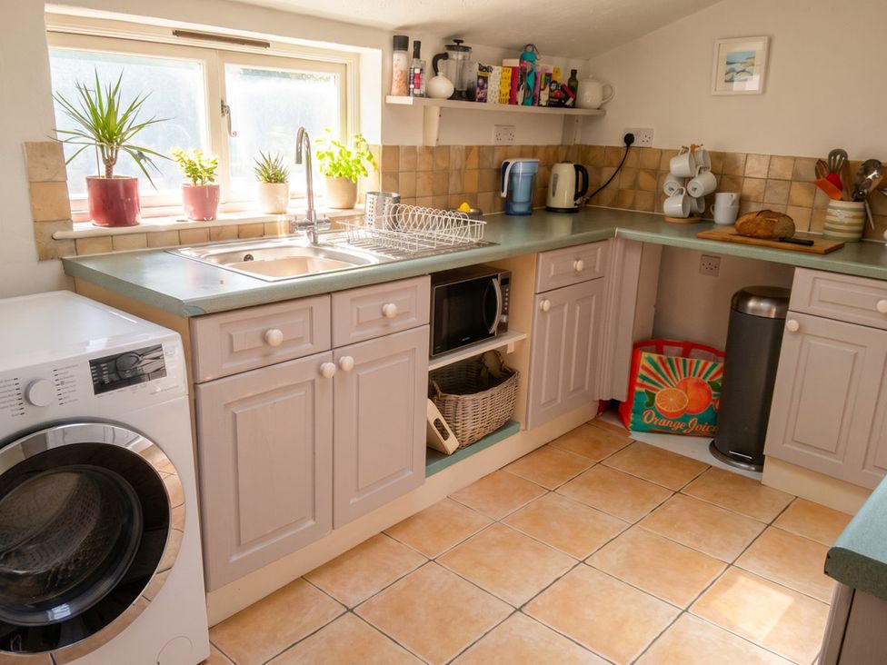 A kitchen with sink, cabinets, washing machine, and microwave at The Old Barn in Manchester