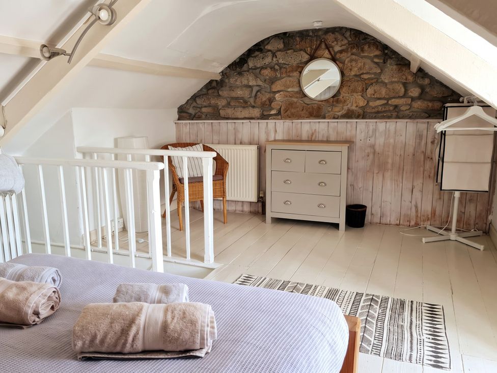 A bedroom with a bed, dresser, chair, and mirror at The Old Barn in Manchester