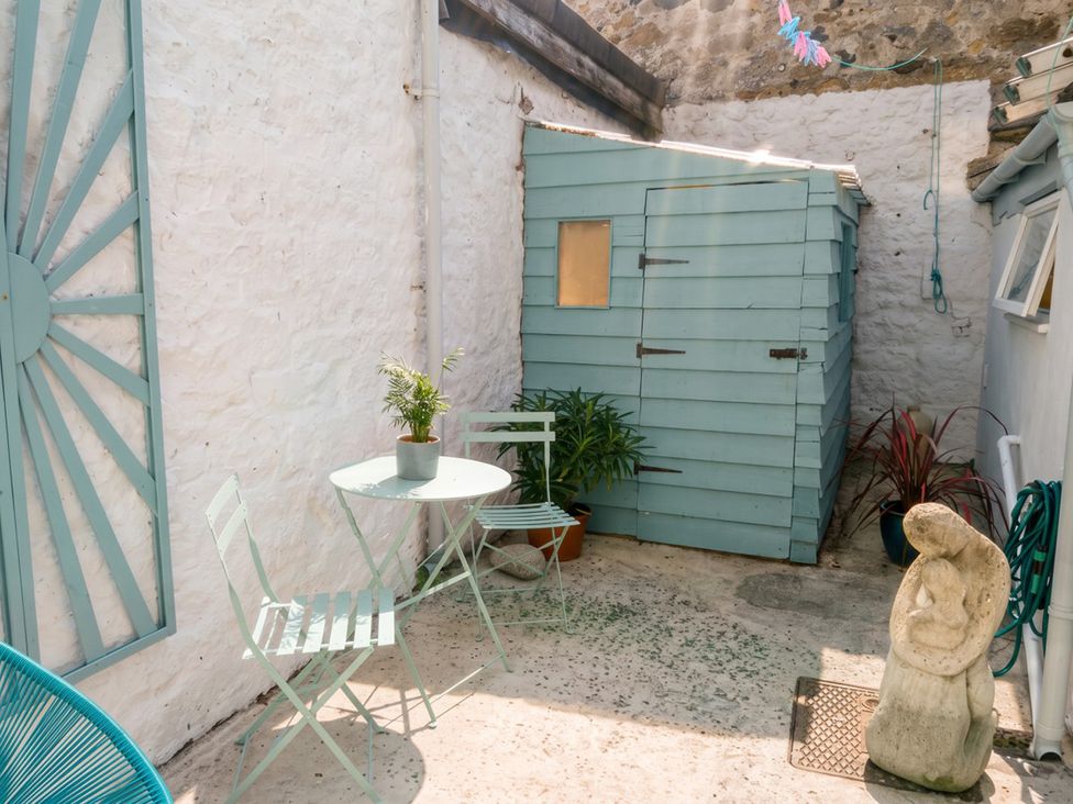 A garden with a shed, table, chairs, and plants in a courtyard