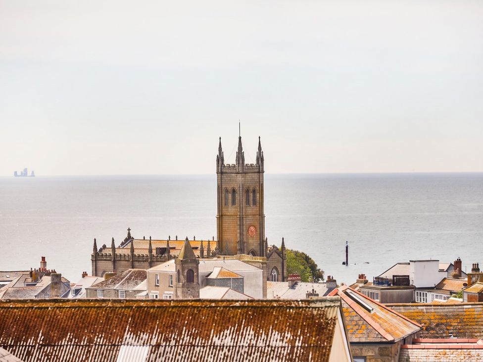 A view of rooftops and a church tower by the ocean