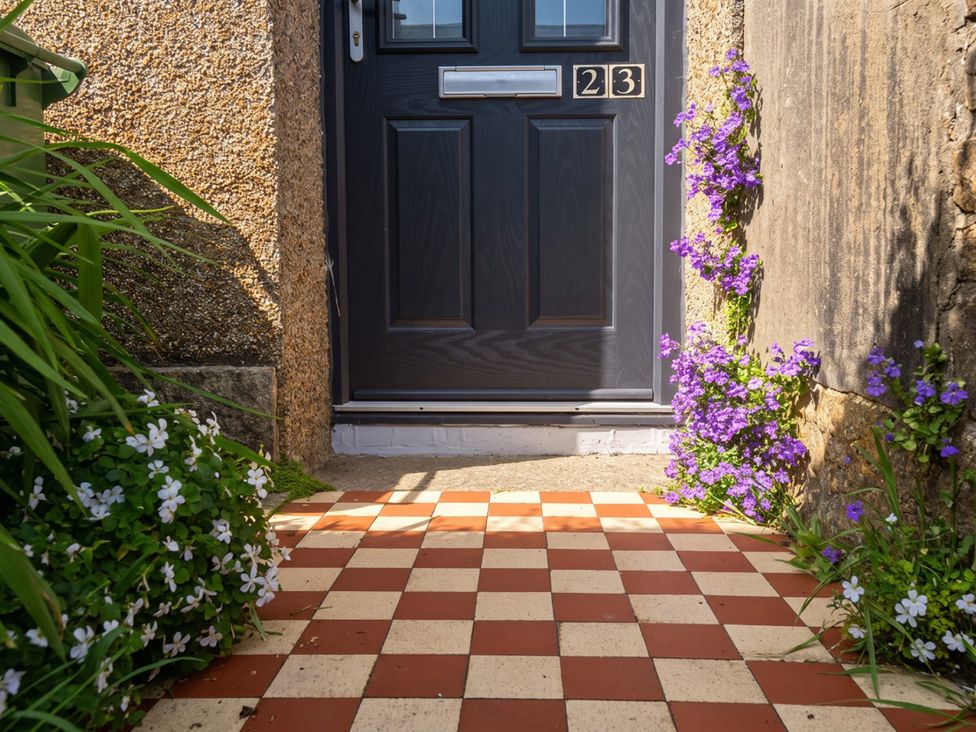 A doorway with a flower bed and a brick pathway at 23