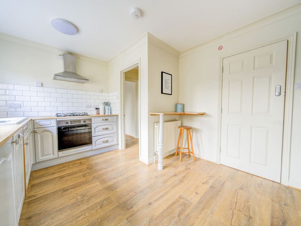 A kitchen with a gas stovetop, oven, and a small table at The Old Barn in Manchester