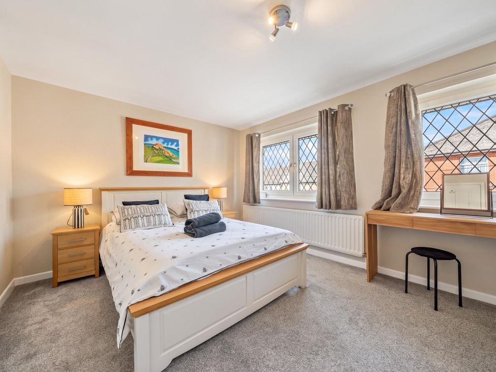 A bedroom with a bed, desk, and windows at the property