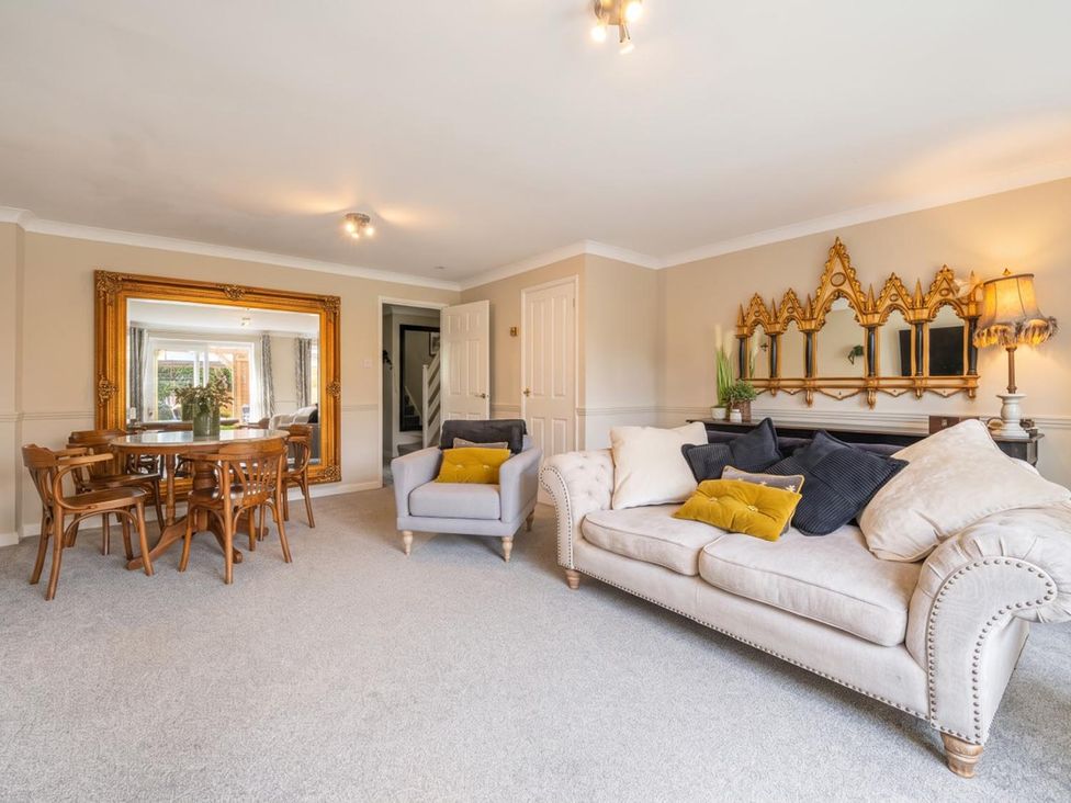 A living room with a dining area and a large mirror at a property location