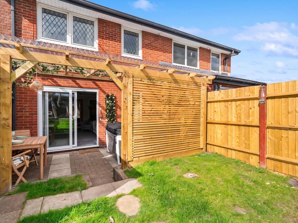 A garden with a wooden pergola and table at the property in the UK