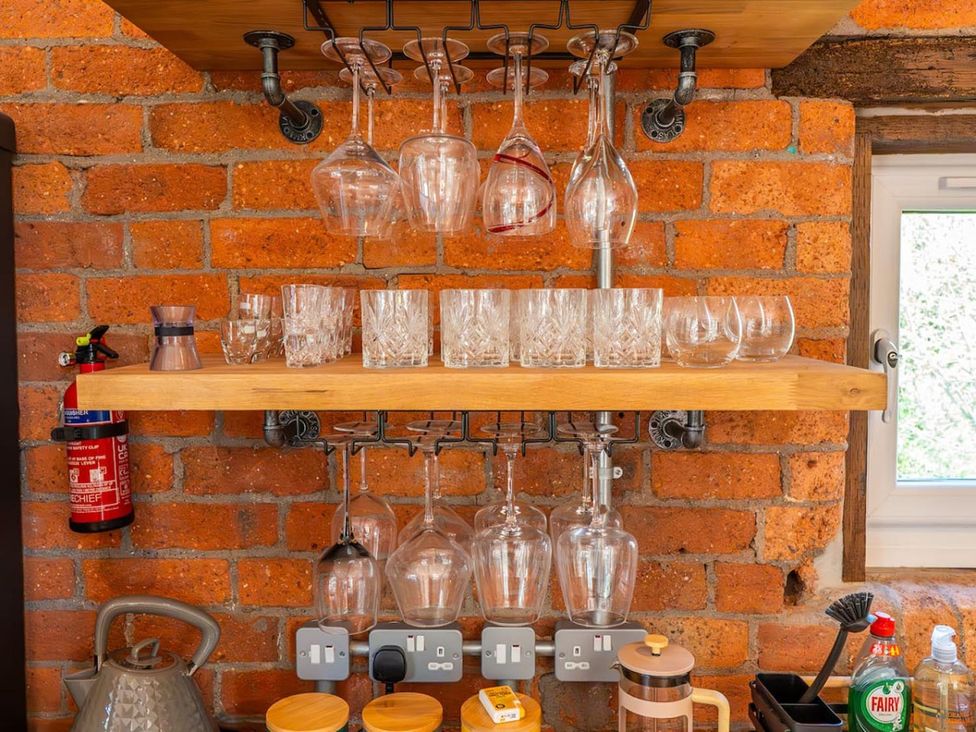 A kitchen area with glassware hanging on shelves and a fire extinguisher at the property in 