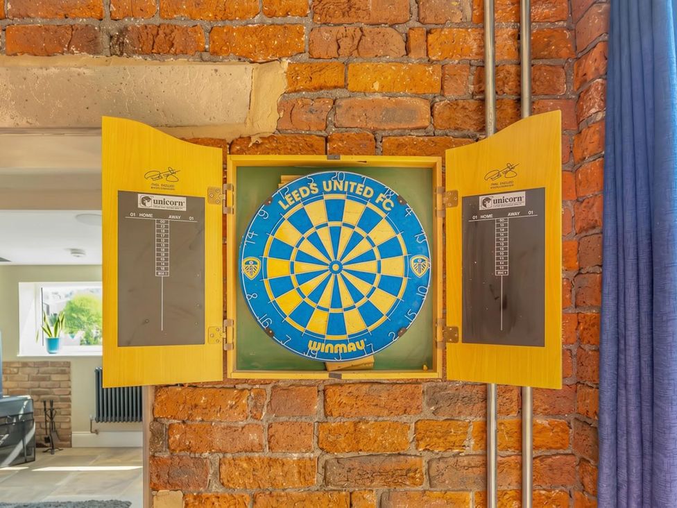 A dartboard mounted on a wall with a scoring board at a games room in a property