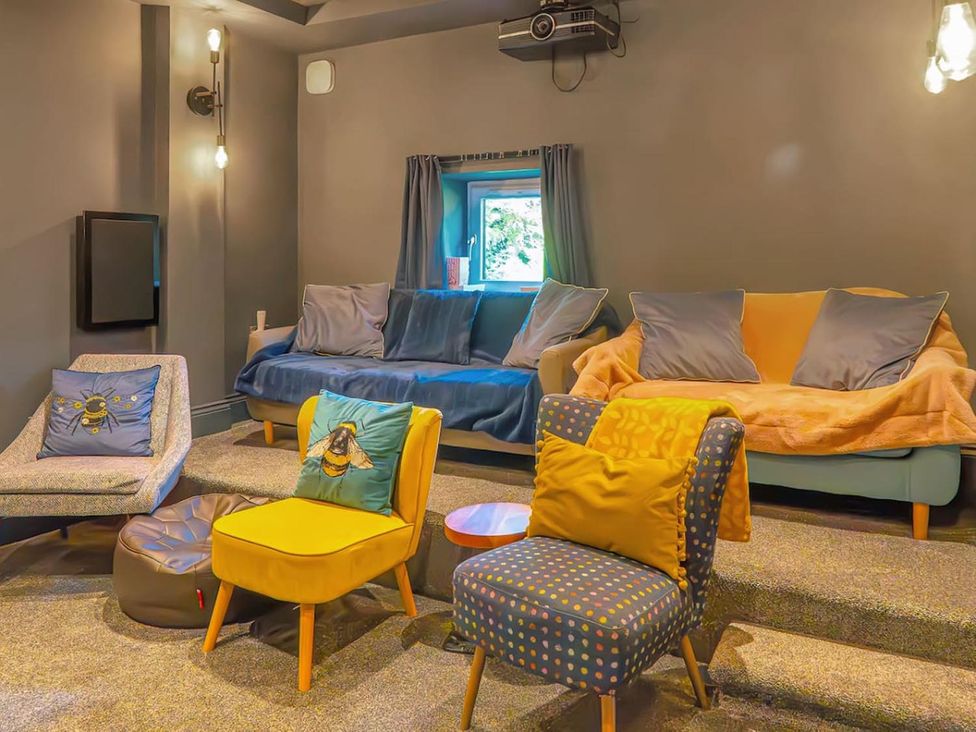 A home theater with sofas, chairs, and a projector at The Old Barn in Manchester