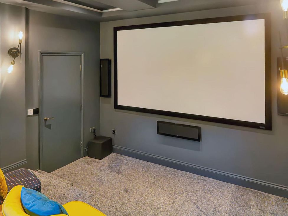 A home theater with a projector screen and light fixtures in a gray room