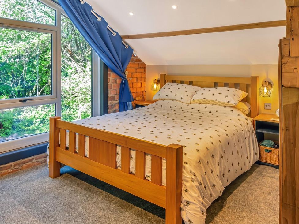 A bedroom with a wooden bed and large window at 