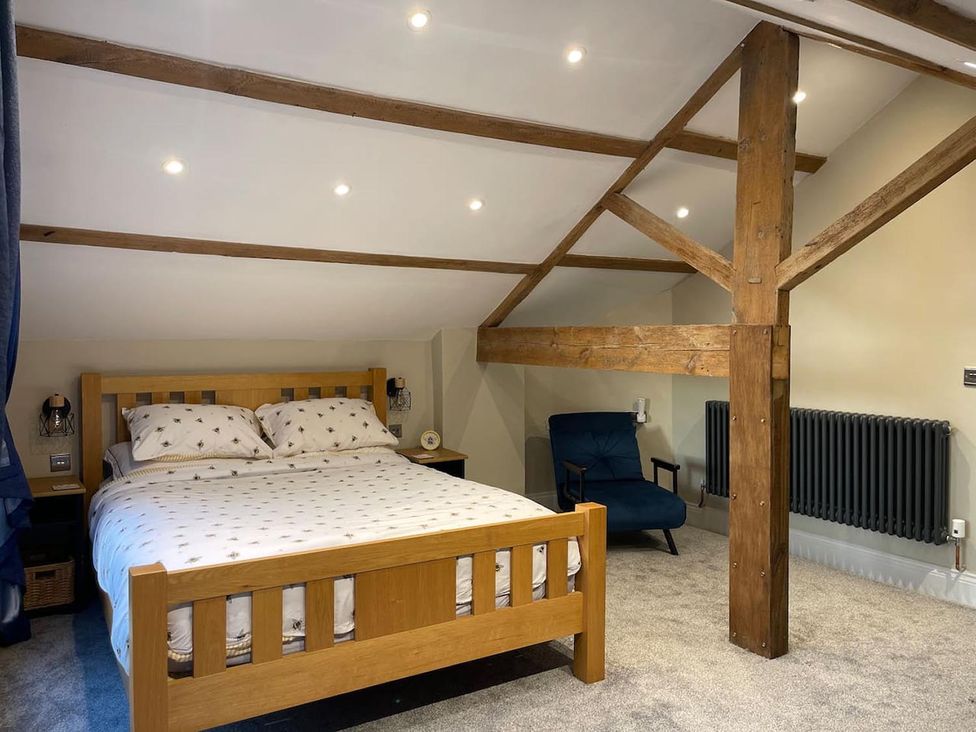 A bedroom with a bed, chair, and radiator at The Old Barn in Manchester