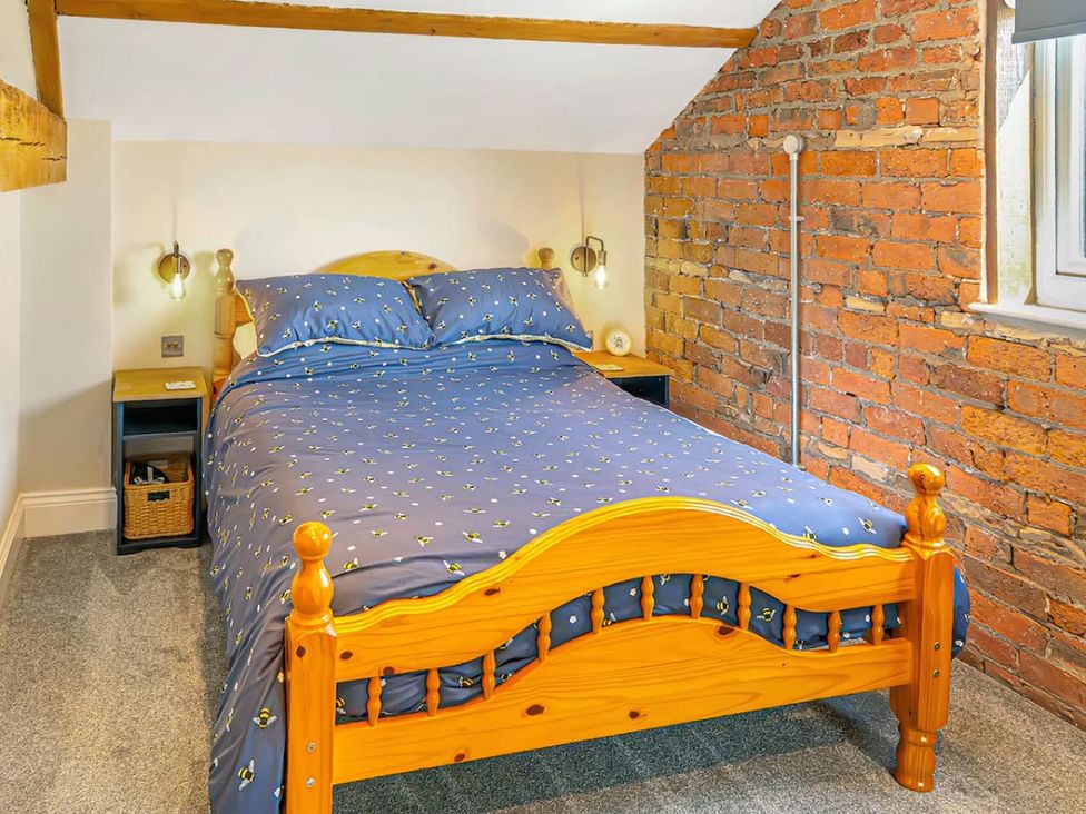 A bedroom with a wooden bed and a nightstand at The Old Barn in Manchester