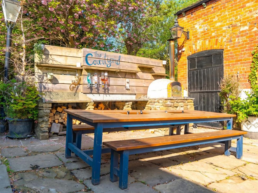 A courtyard with a wooden table and benches at The Courtyard in an outdoor setting