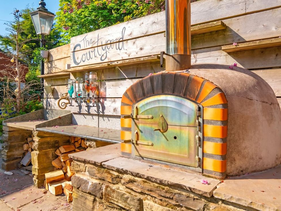 A pizza oven and wood storage in an outdoor space at The Courtyard in an unspecified location