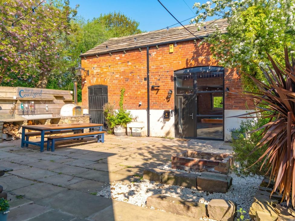 A courtyard with a brick wall and a table at The Courtyard in an outdoor setting