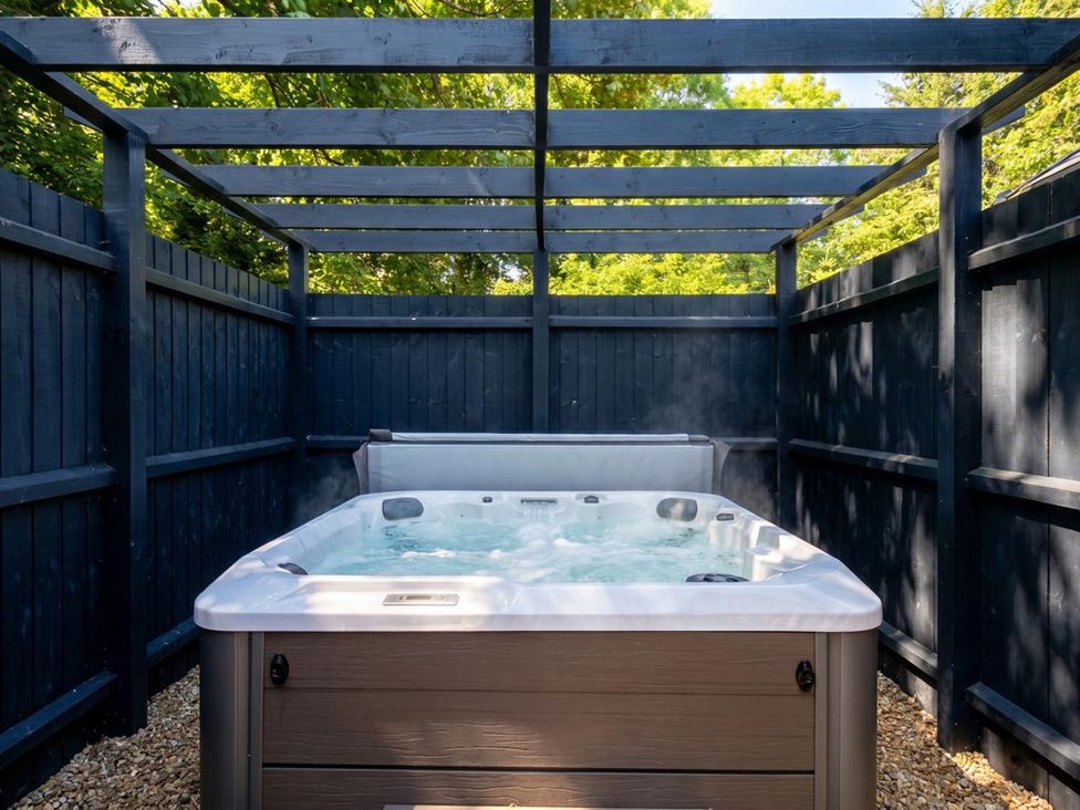 A hot tub surrounded by wooden fence in a garden