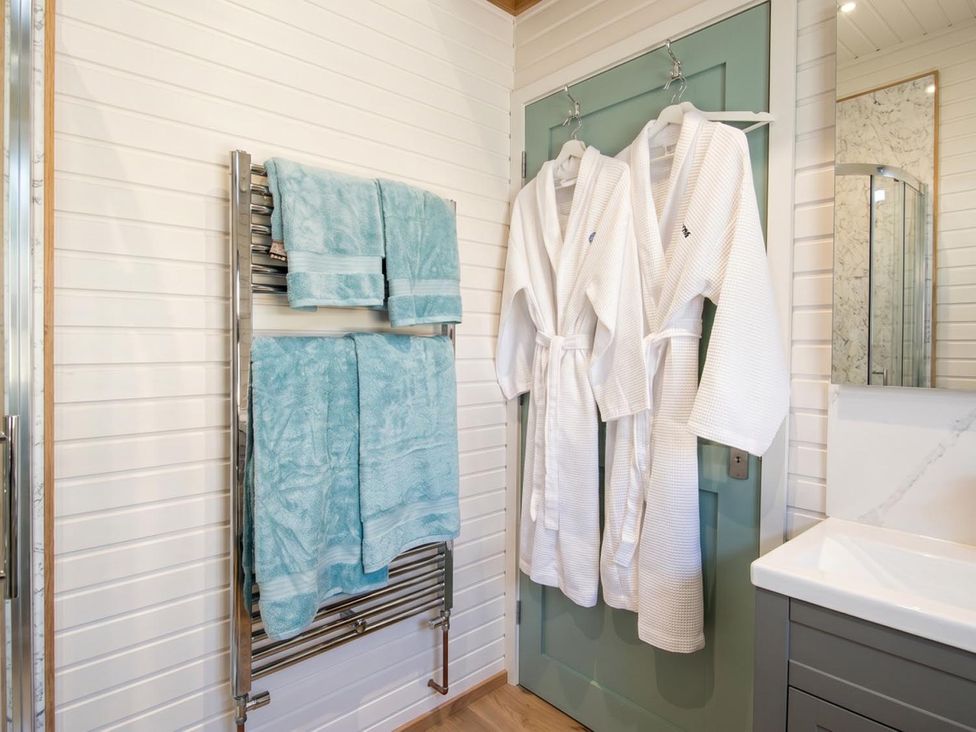 A bathroom with towels, bathrobes, and a sink at The Old Barn in Manchester