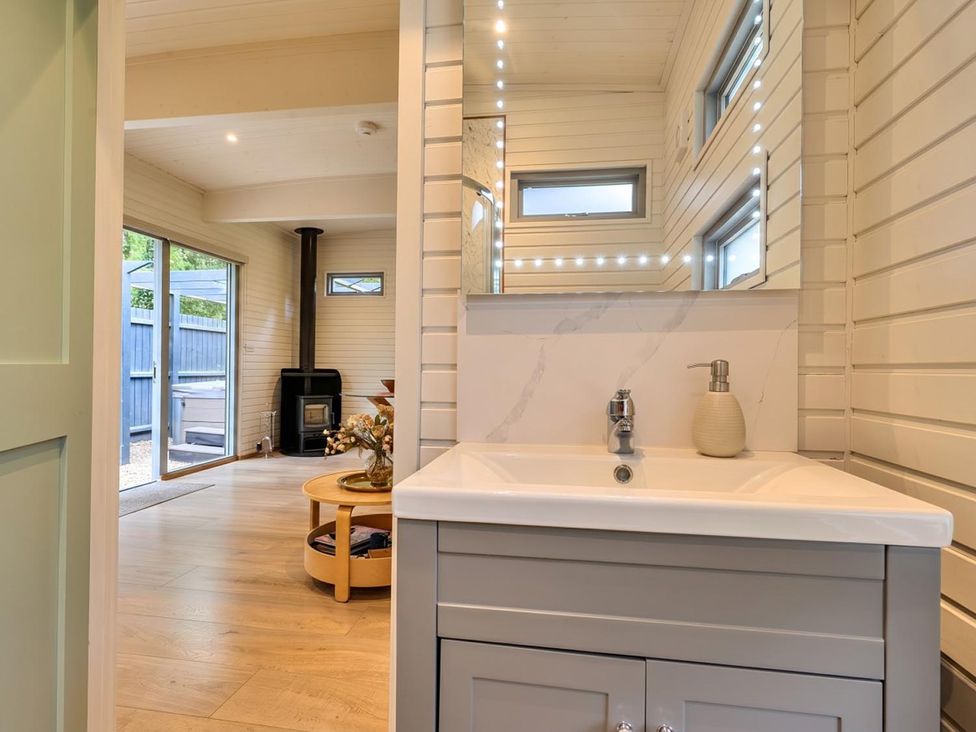 A bathroom with a sink and mirror leading to a living area at The Old Barn in Manchester