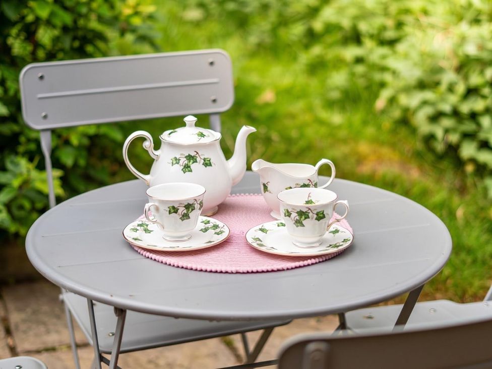 A teapot and cups on a table at an outdoor dining area