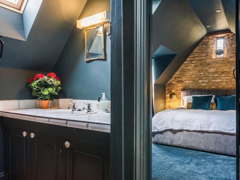 A bathroom with sink and mirror leading to a bedroom at The Old Barn in Manchester