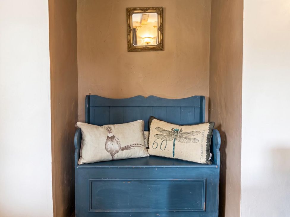A bench with pillows and a mirror in an entryway at The Old Barn in Manchester