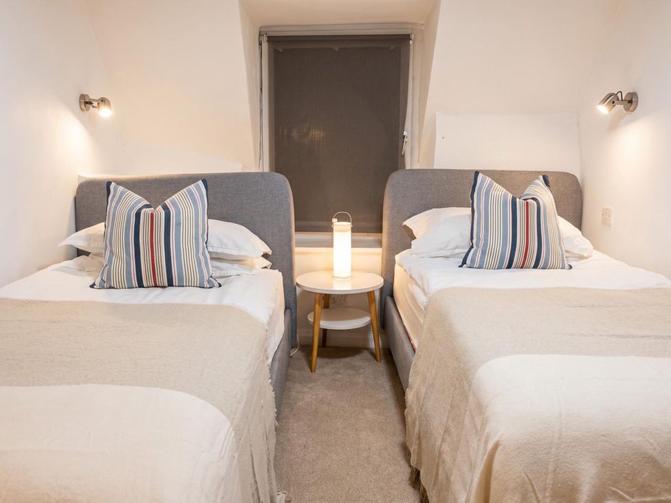 A bedroom with two beds and a lamp on a nightstand at 