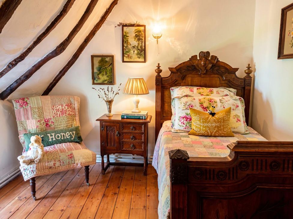 A bedroom with a bed, nightstand, armchair, and artwork on walls at 