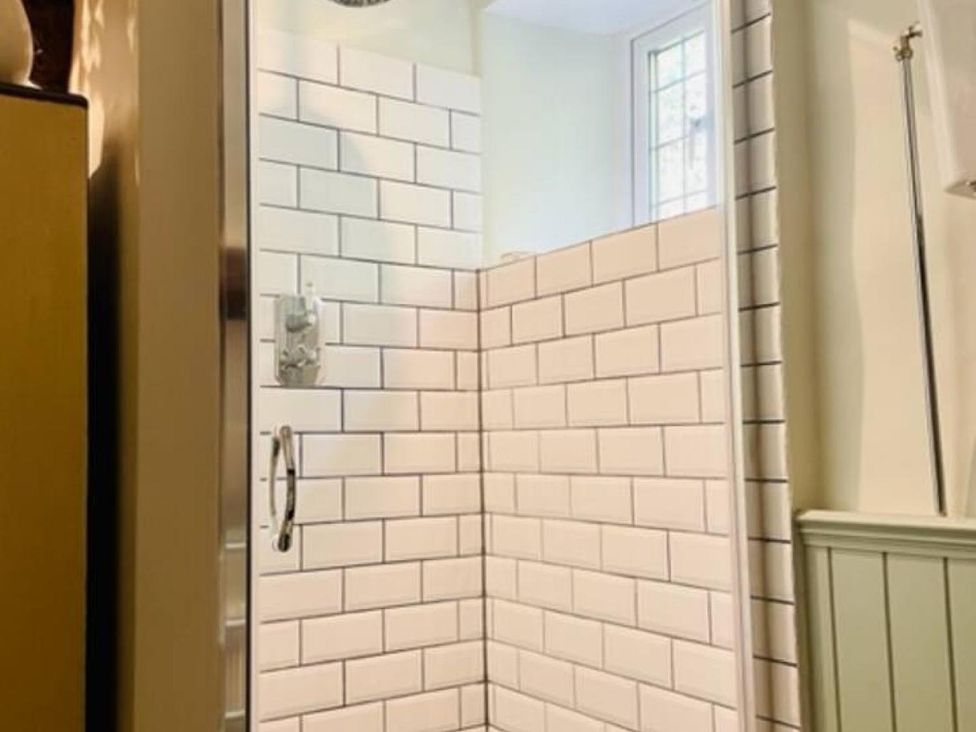 A shower area with tiled walls and a window at the property in 