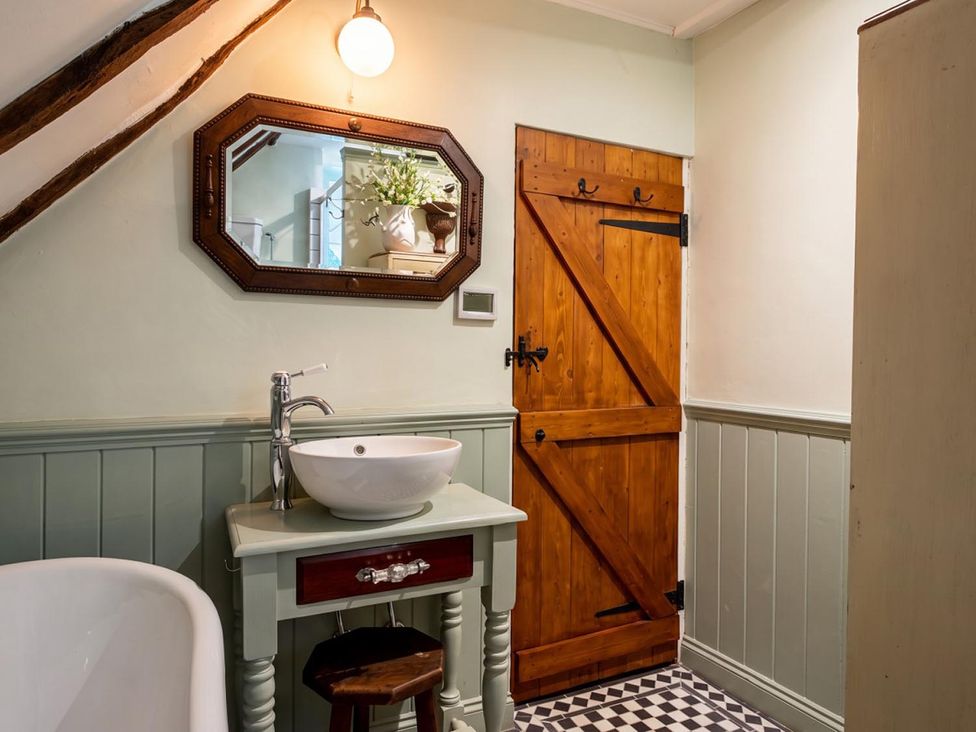 A bathroom with a sink, mirror, and bathtub at The Old Barn in Manchester