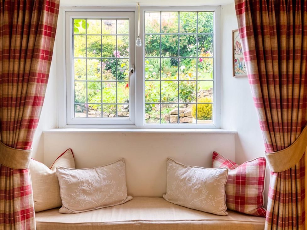 A sitting room with a window and cushions at The Old Barn in Manchester