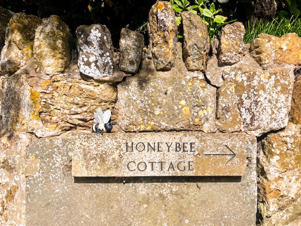 A sign for Honeybee Cottage with a decorative bee at Honeybee Cottage in the garden