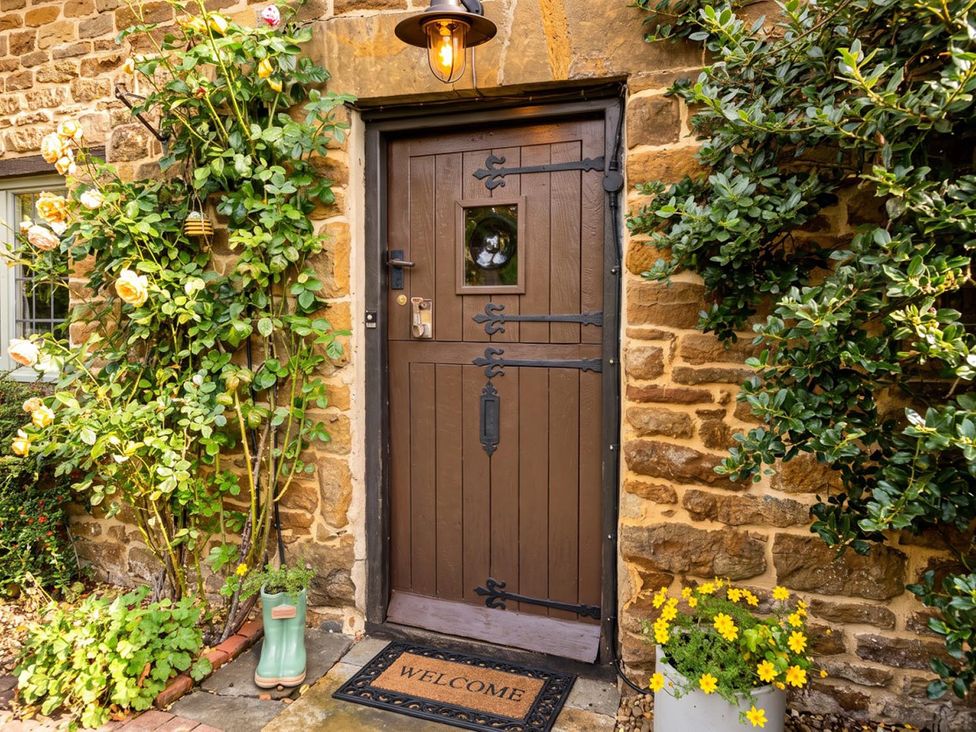 A front door with a welcome mat and flowers at a house in an outdoor setting