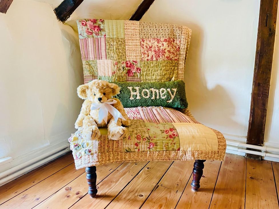 A chair with a quilt and a teddy bear in the sitting room
