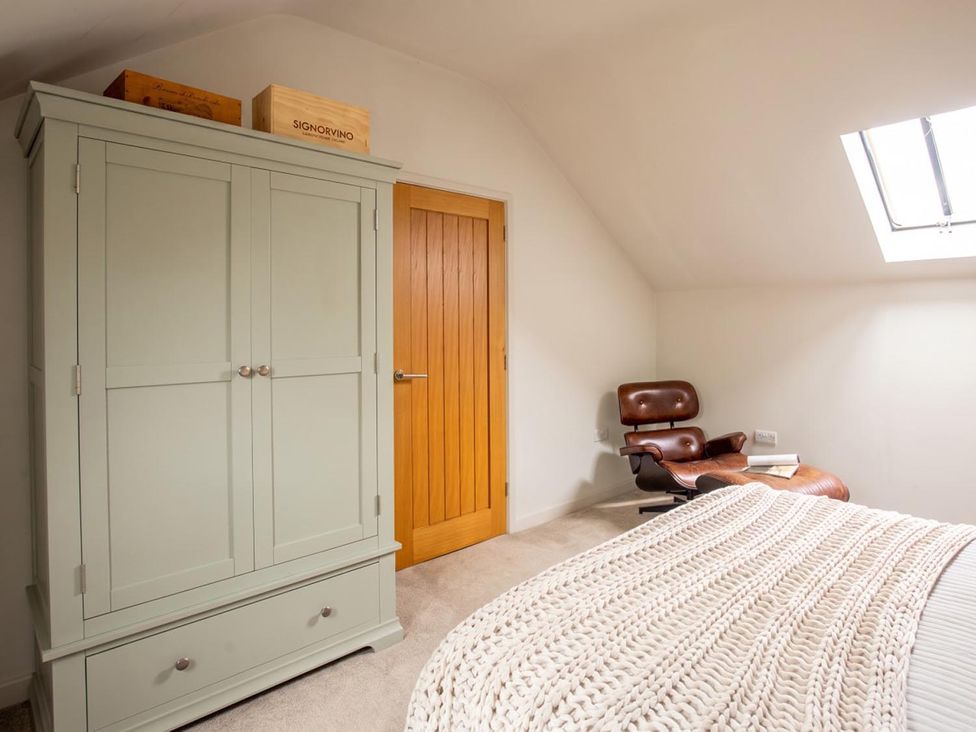 A bedroom with a wardrobe, armchair, and book at The Old Barn in Manchester
