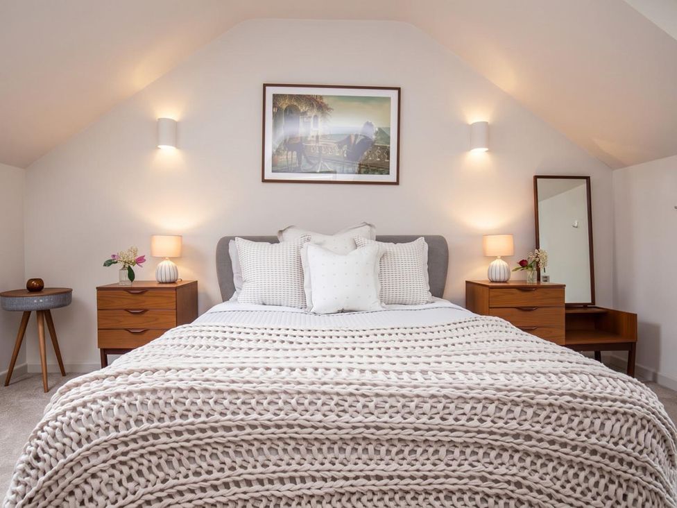 A bedroom with a bed, nightstands, and a mirror at 