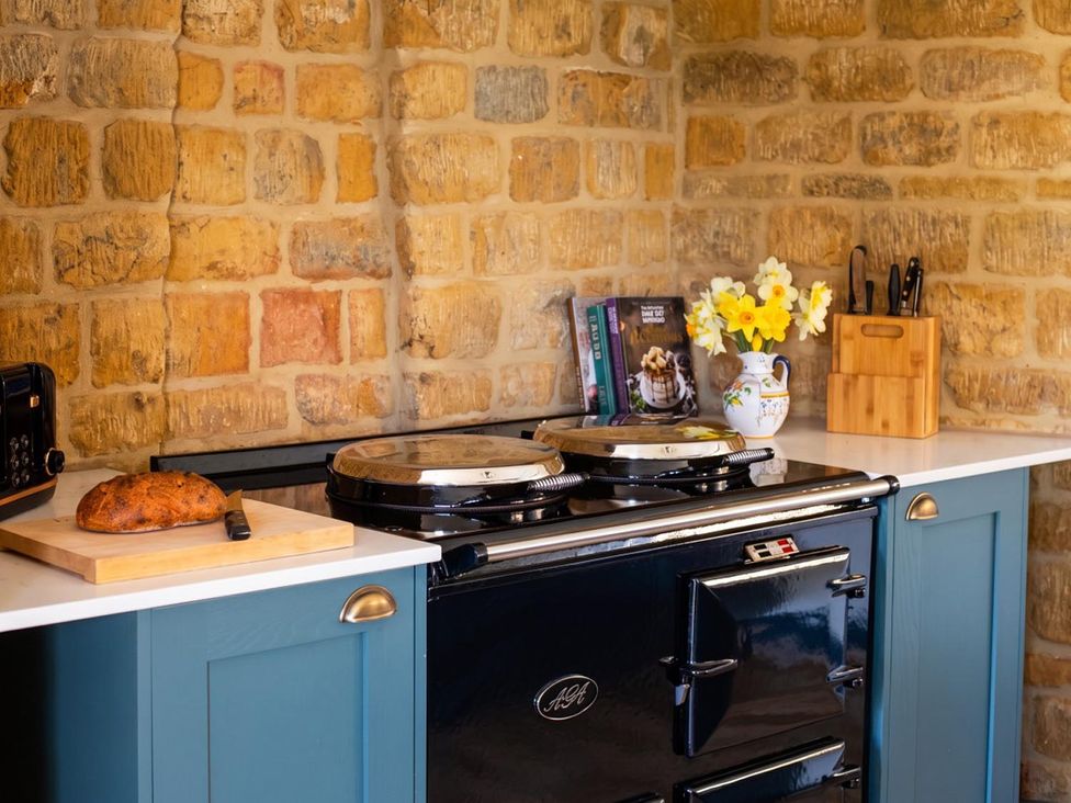 A kitchen with an oven, cutting board, and flowers at The Old Barn in Manchester