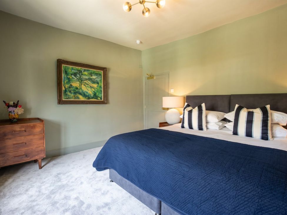 A bedroom with a bed, dresser, and a painting at The Old Barn in Manchester