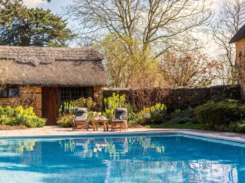 An outdoor area with a swimming pool and thatched roof house at the property
