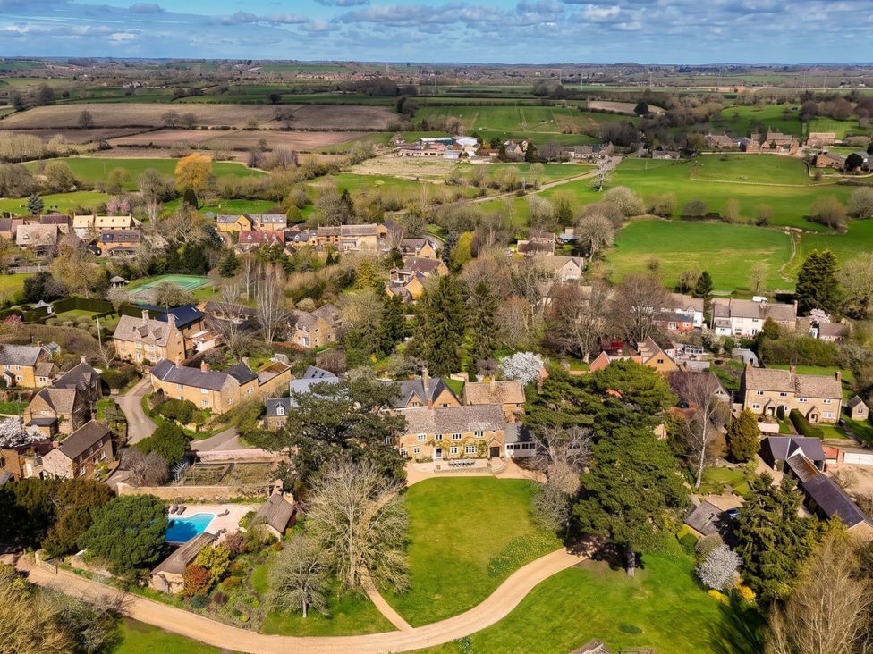 An aerial view of houses and greenery with a pool and garden at the property