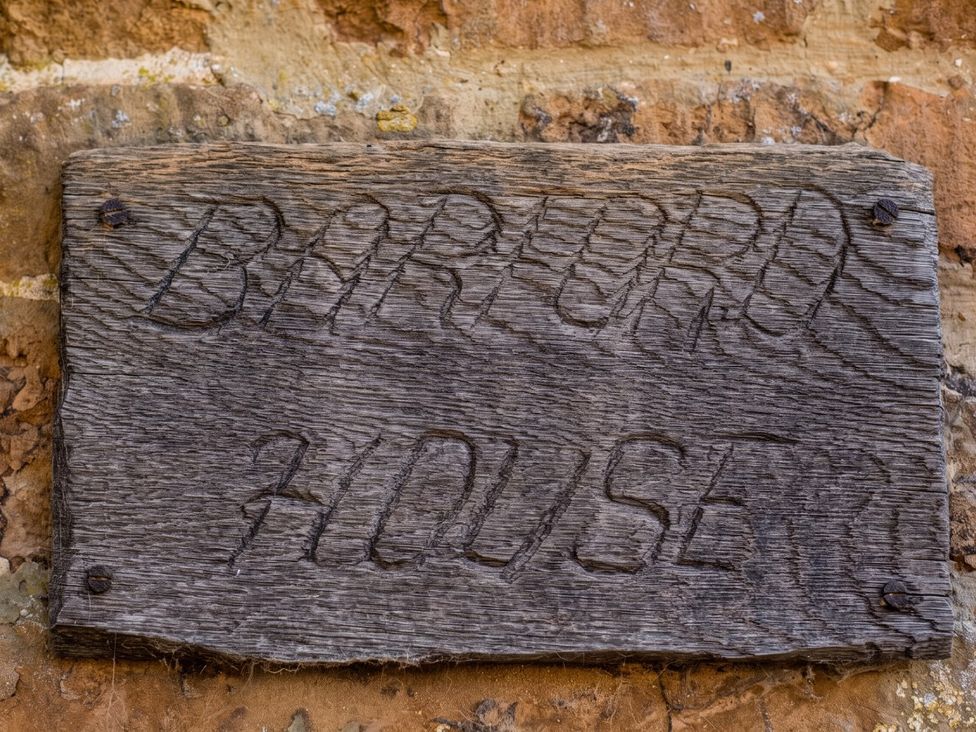 A wooden sign with engraved text at a location named Barford House
