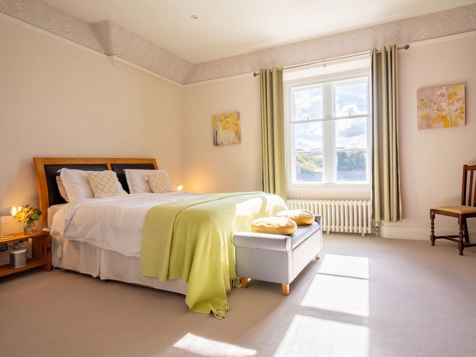 A bedroom with a bed, side table, lamp, and chair at The Old Barn in Manchester