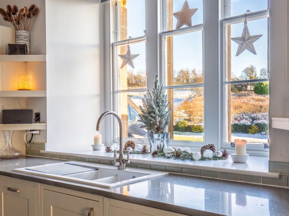 A kitchen with a sink and window showing a winter view at The Old Barn in Manchester
