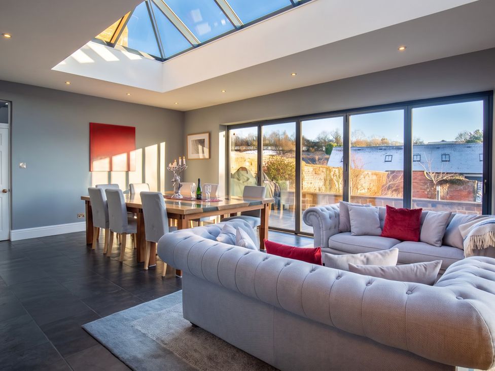 A dining room with a table and chairs by large windows at 