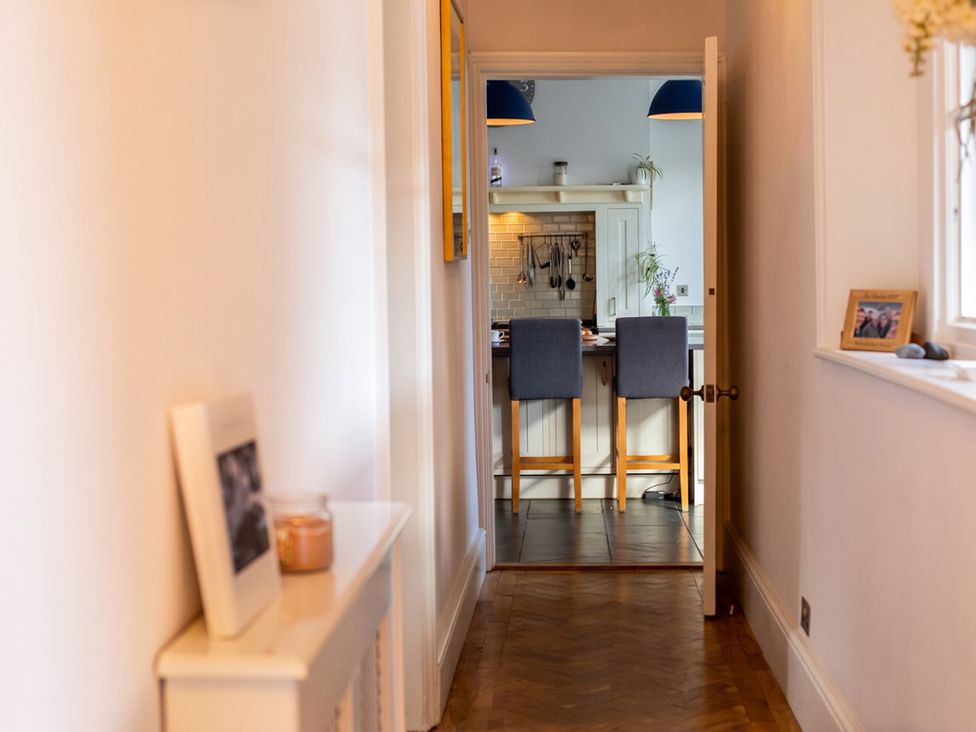 A hallway leading to a kitchen with bar stools at an unknown property in an unknown location