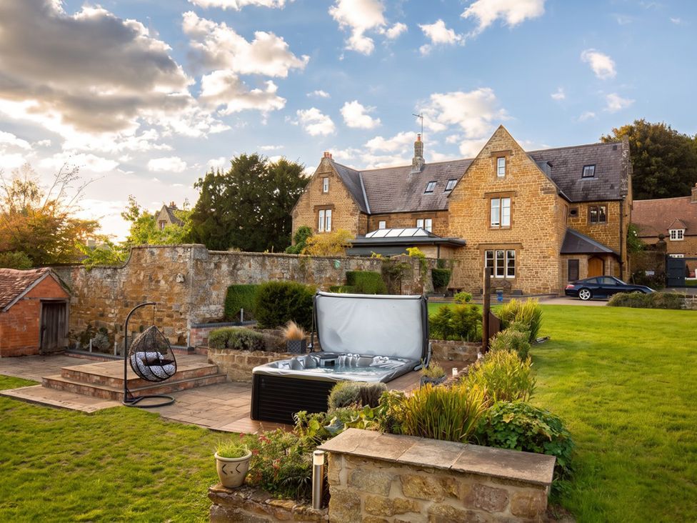 A garden with a hot tub and hanging chair at a property