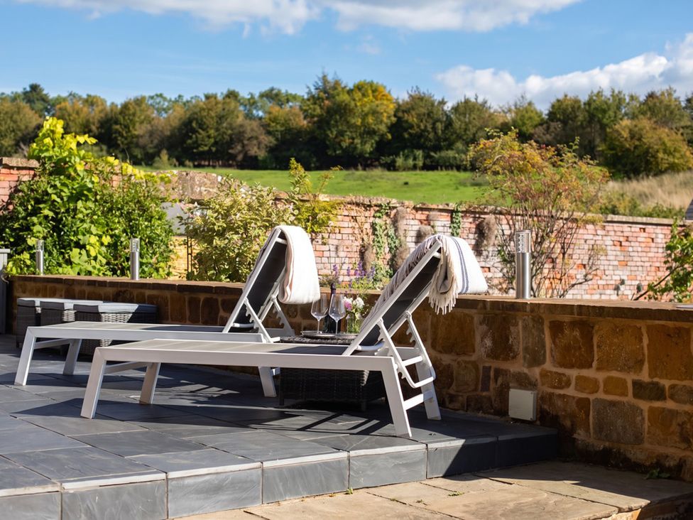 Lounge chairs and table with wine glasses on an outdoor patio at the property