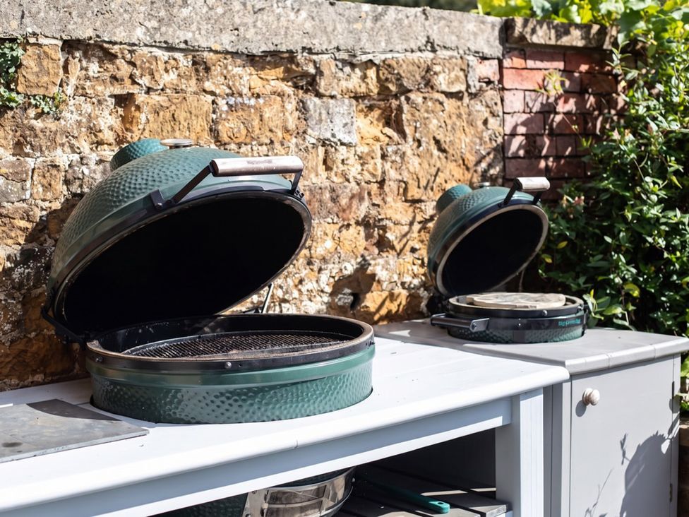 An outdoor kitchen with two grills and a stone wall at the property location